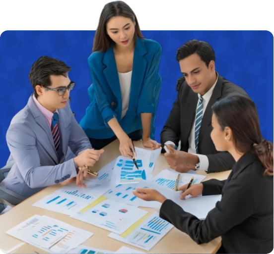 A group of four team professionals are collaborating on documents at a table. This relates to Custom CRM Software Development Company services.